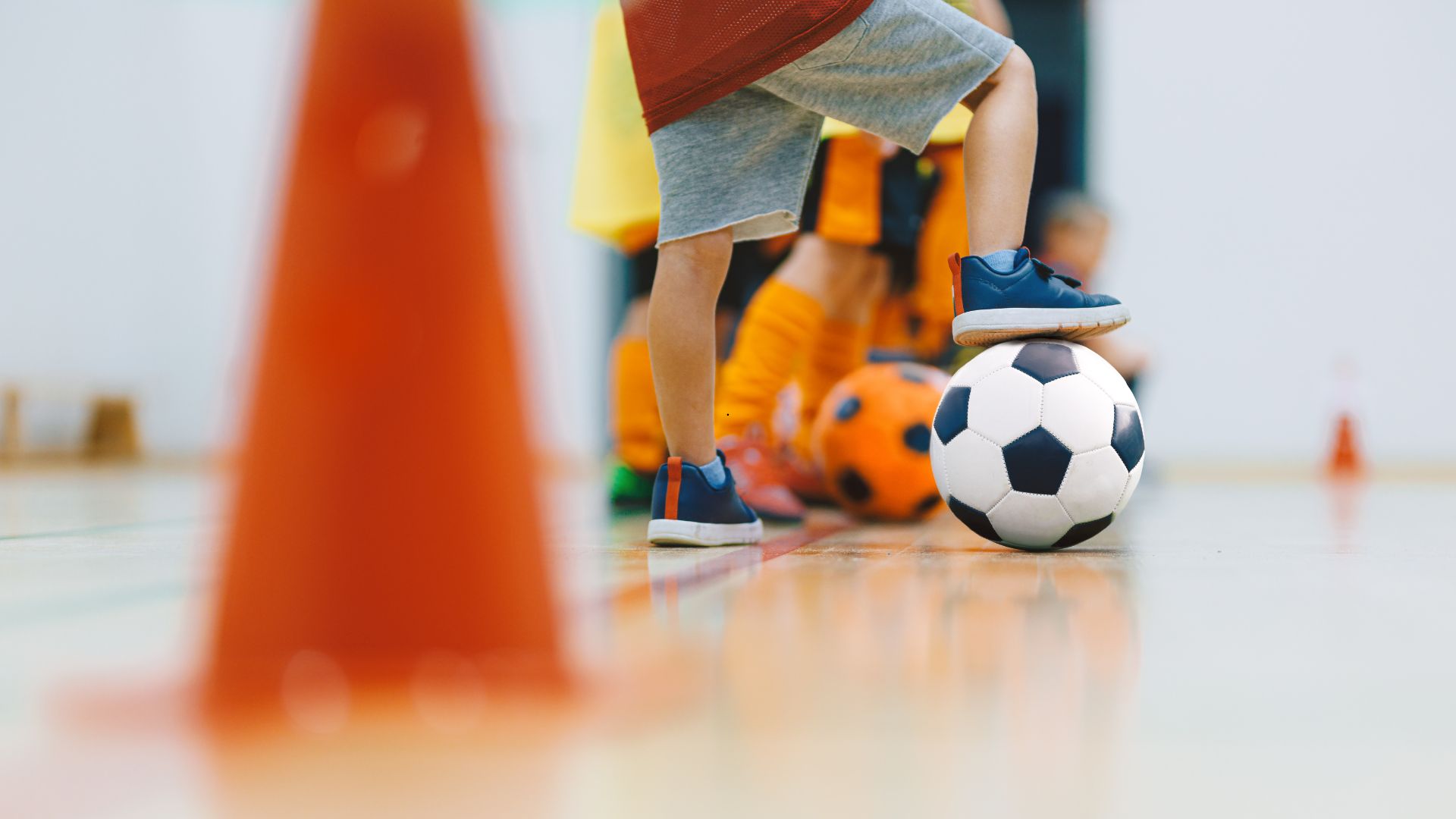 Kind mit Fussball in Turnhalle